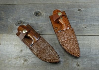 Two palm skinner knives inside handcrafted leather sheaths