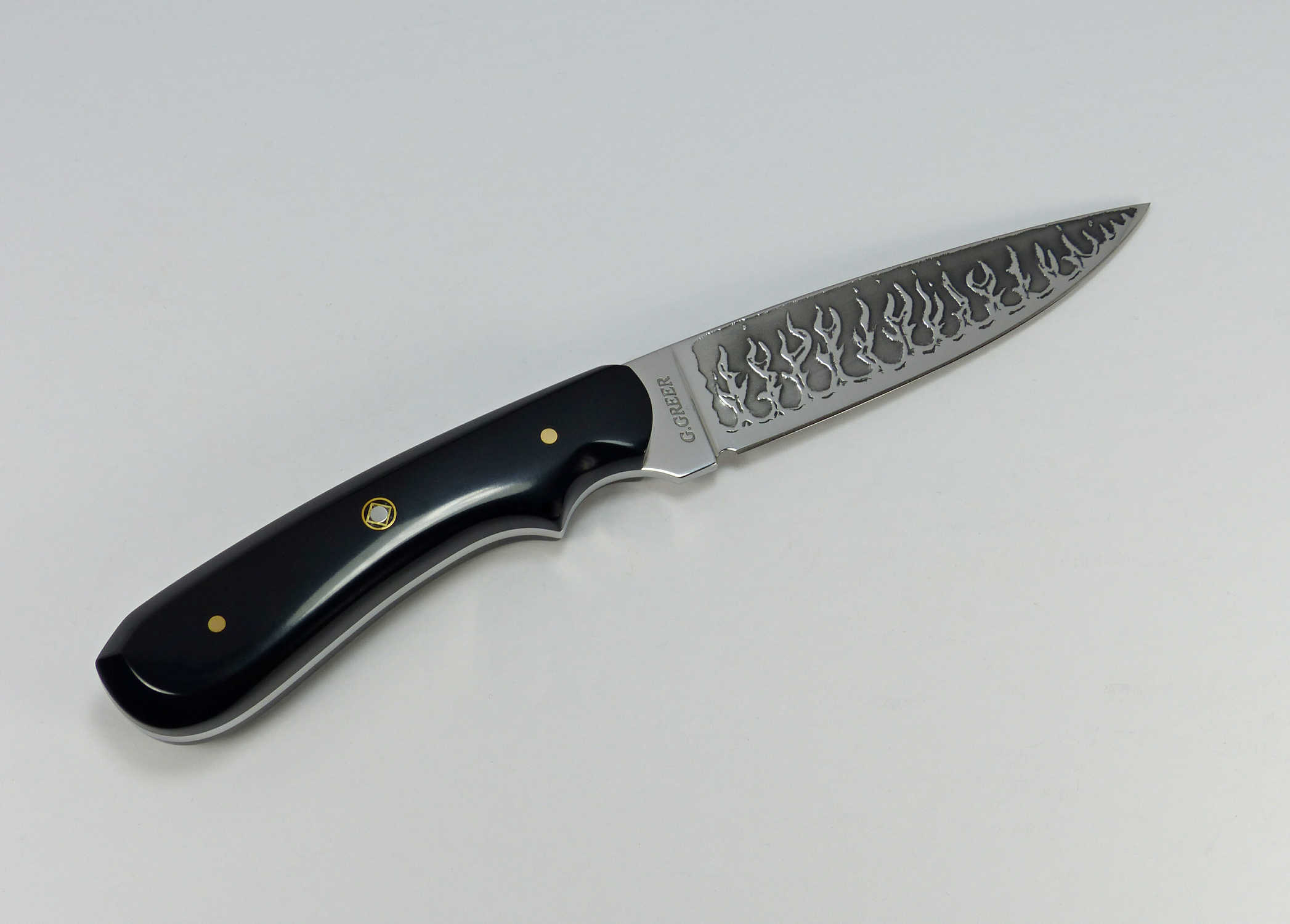 Black handled art knife with flames etched into blade of knife
