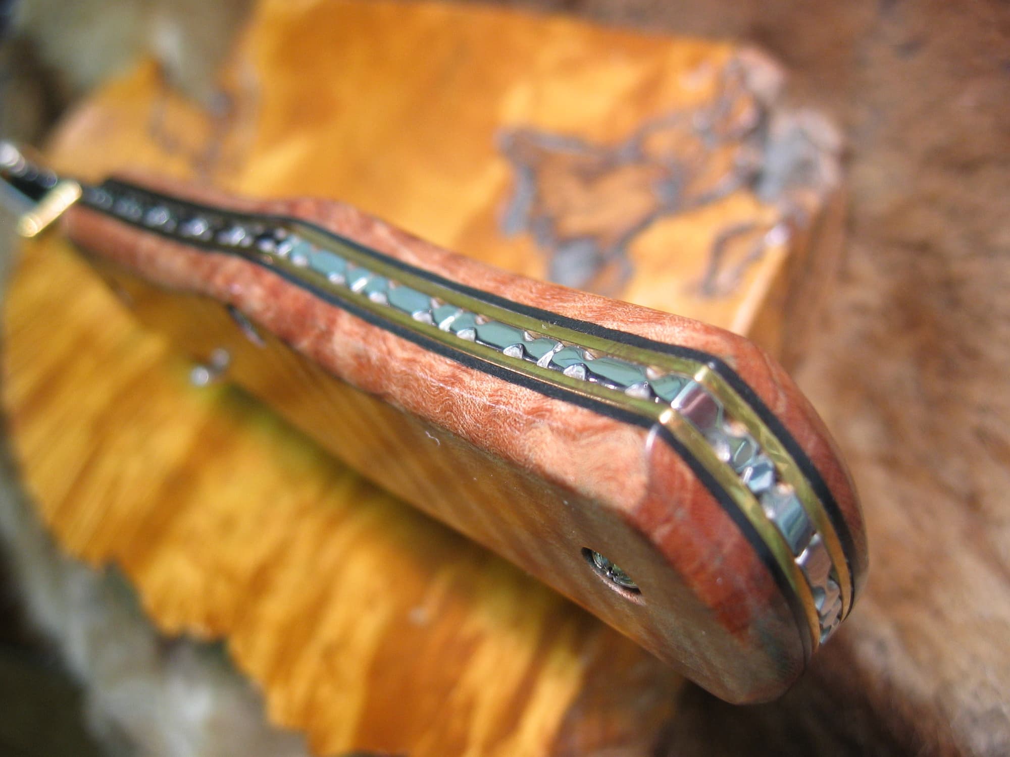 Flame maple handle of folding knife showing liners and filework