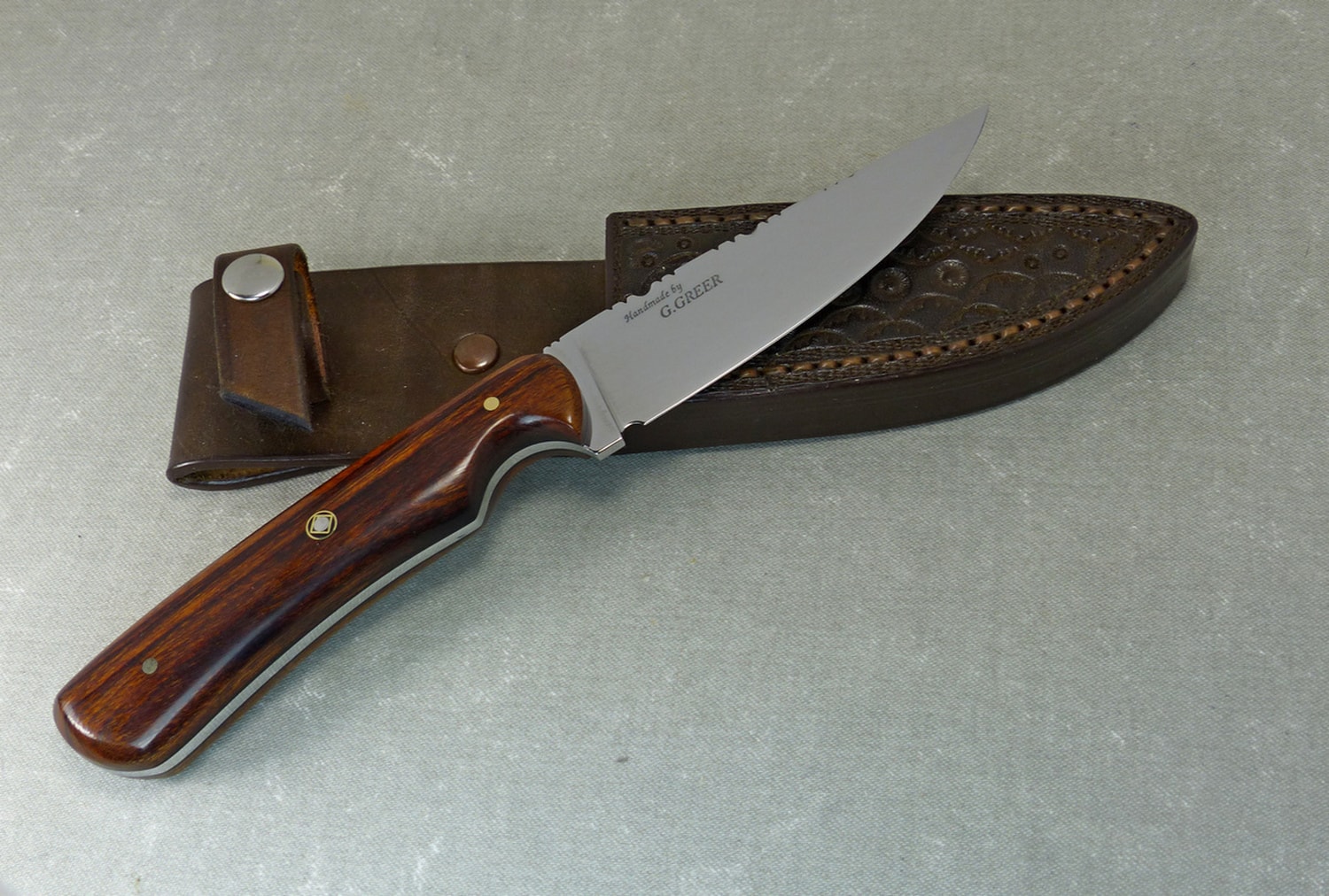 015 Brown Arizona Desert Ironwood hunting knife resting on hand tooled leather sheath
