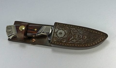 Brown wood handled art knife inside brown hand tooled leather sheath