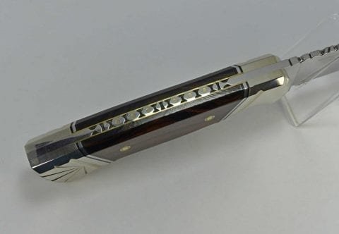 Top of brown knife handle showing brass pins inserted into complex filework