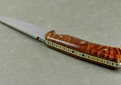 Brass sections inlaid within intricate fileworked in back of brown knife handle