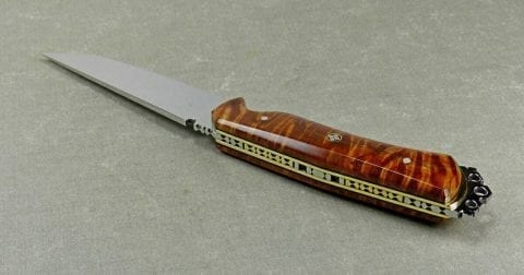 Brass sections inlaid within intricate fileworked in back of brown knife handle