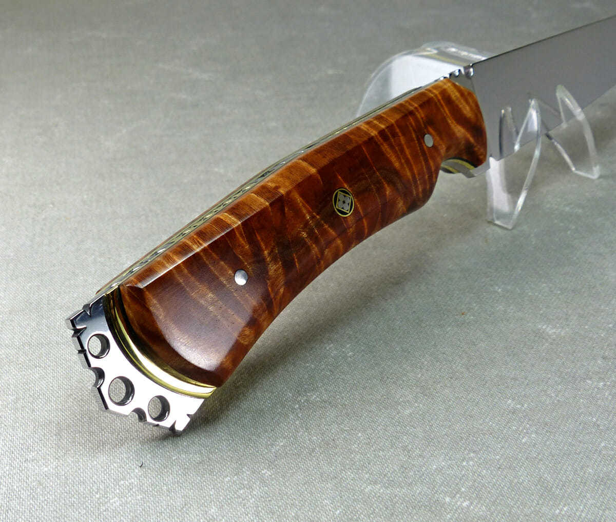 Sculptured metal crown on end of brown flame maple knife handle showing exposed brass plate
