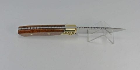 Handmade knife with custom filework on top of wood handle and blade