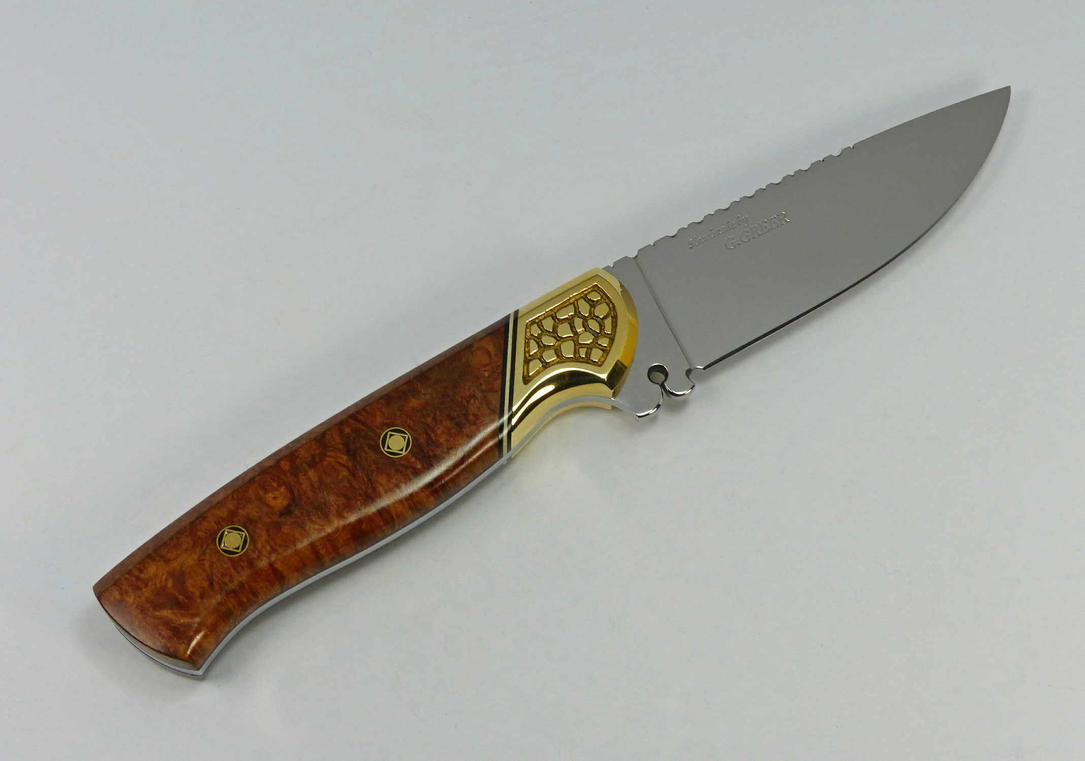 Knife with lustrous brown wood handle topped with engraved brass section fitted to a blade with ricasso