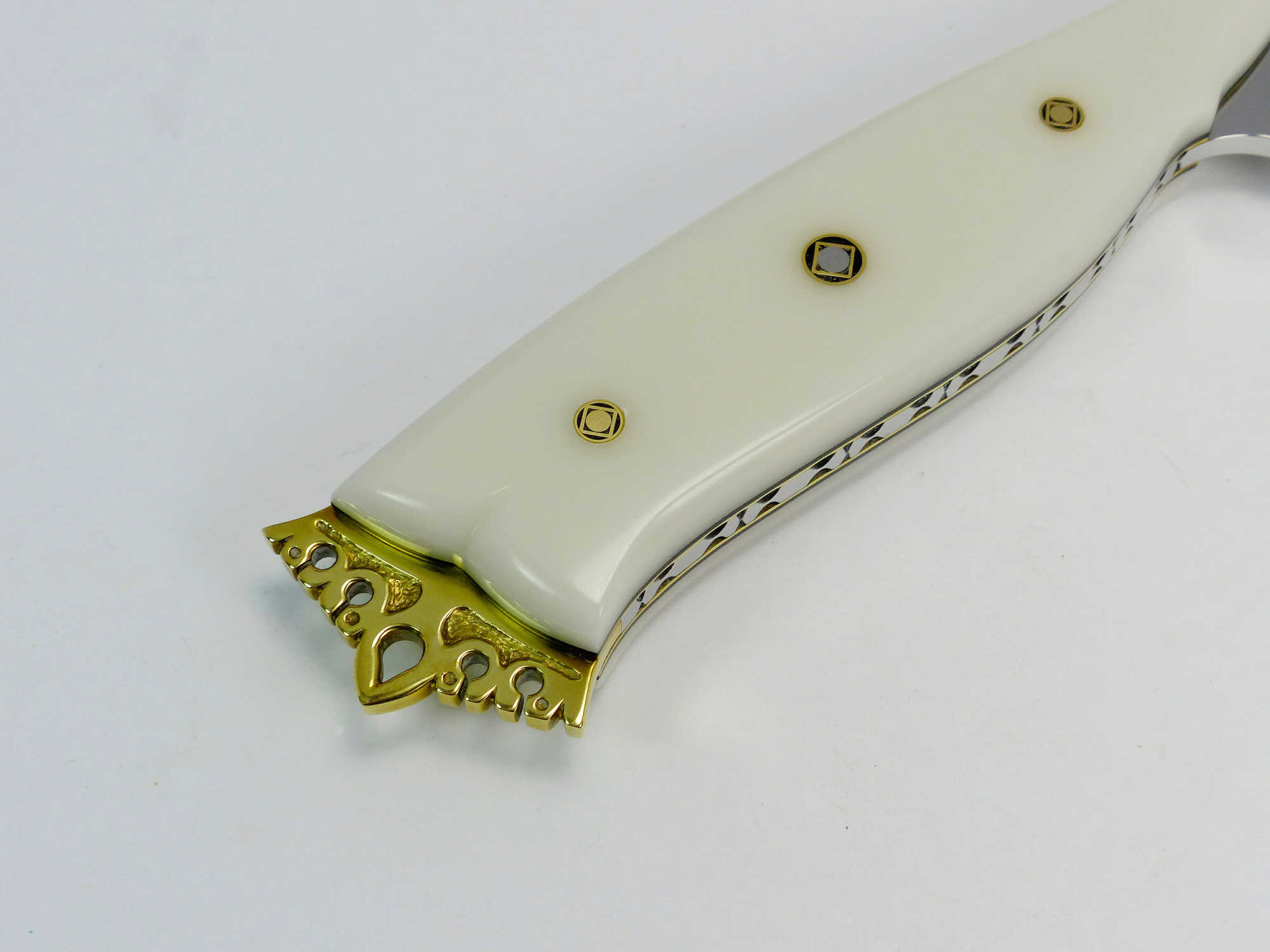 White handled show knife with custom carved brass crown on end of knife