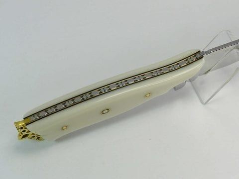 Top of white handled knife showing complex tang filework on high-end art knife