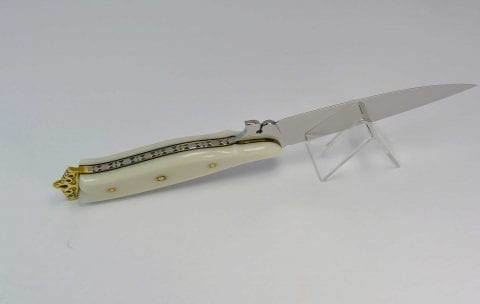 Ornate tang filework on bottom of white knife handle along side pierced ricasso blade