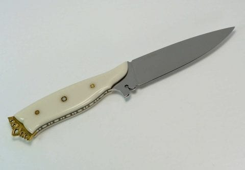 Fancy knife with ornate filework on bottom of white handle, brass crown at end of handle and pierced ricasso blade