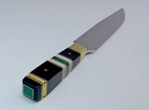 Square polished green stone set into end of black knife handle