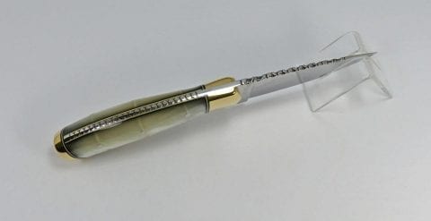 Beautiful filework on top of white pearl colored knife handle and blade of knife