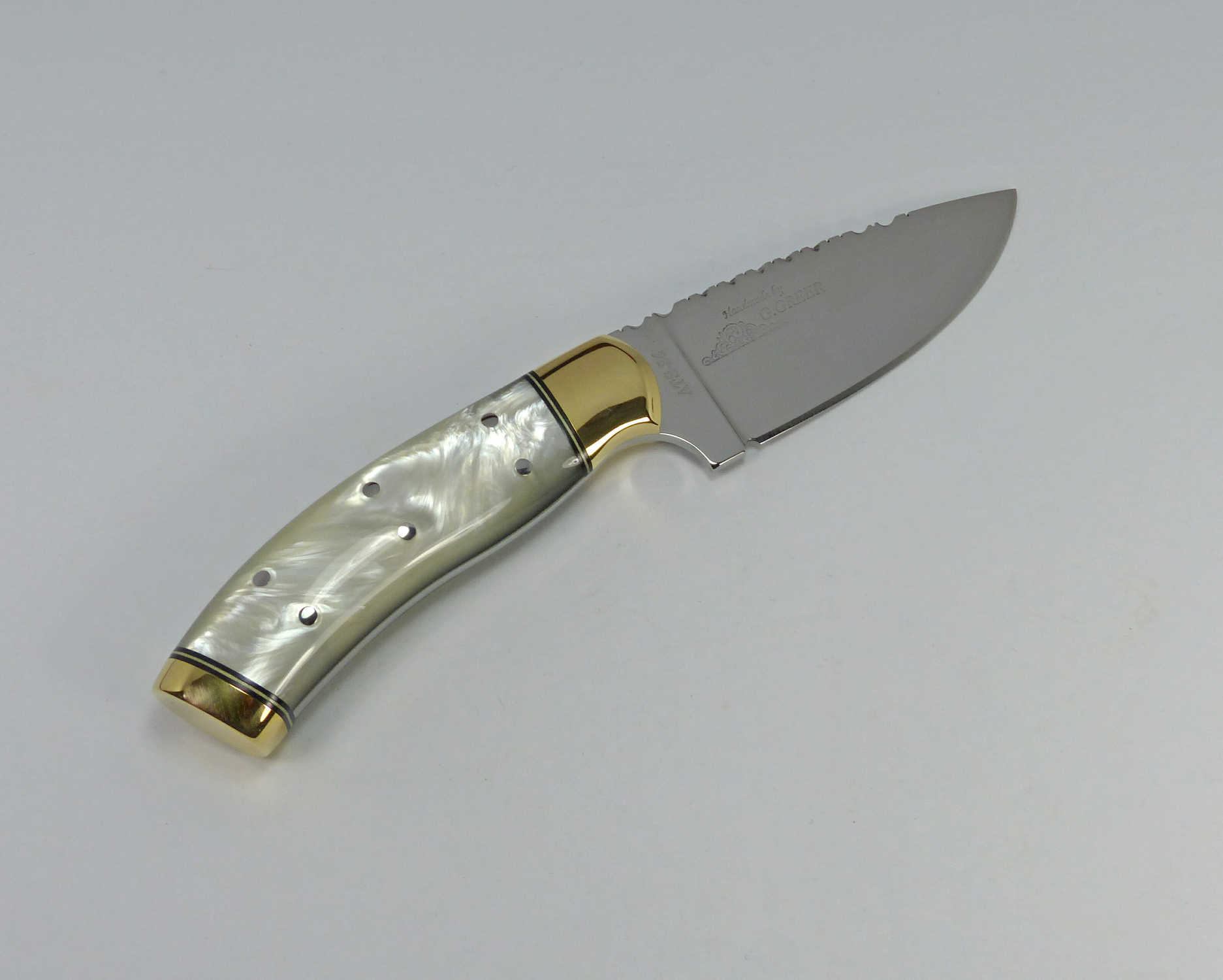 Fancy hunting knife with white pearl polymer handle and brass on front and rear of knife