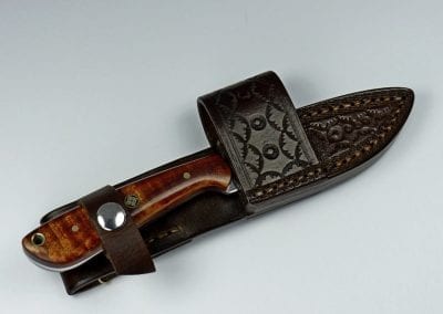 Brown handled knife inside handmade brown leather sheath