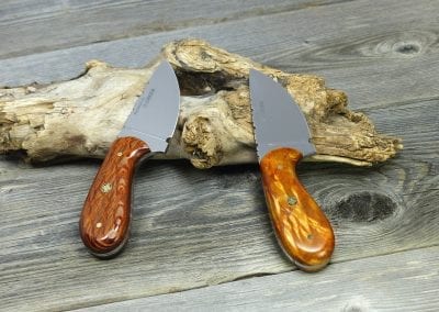 Two wood handled hunting knives resting on log