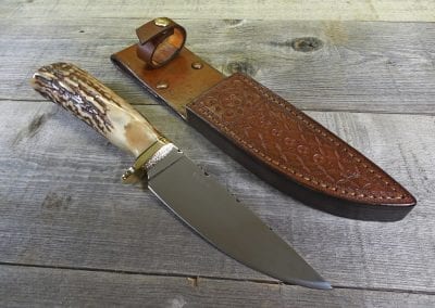Elk horn hunting knife beside custom fitted leather sheath
