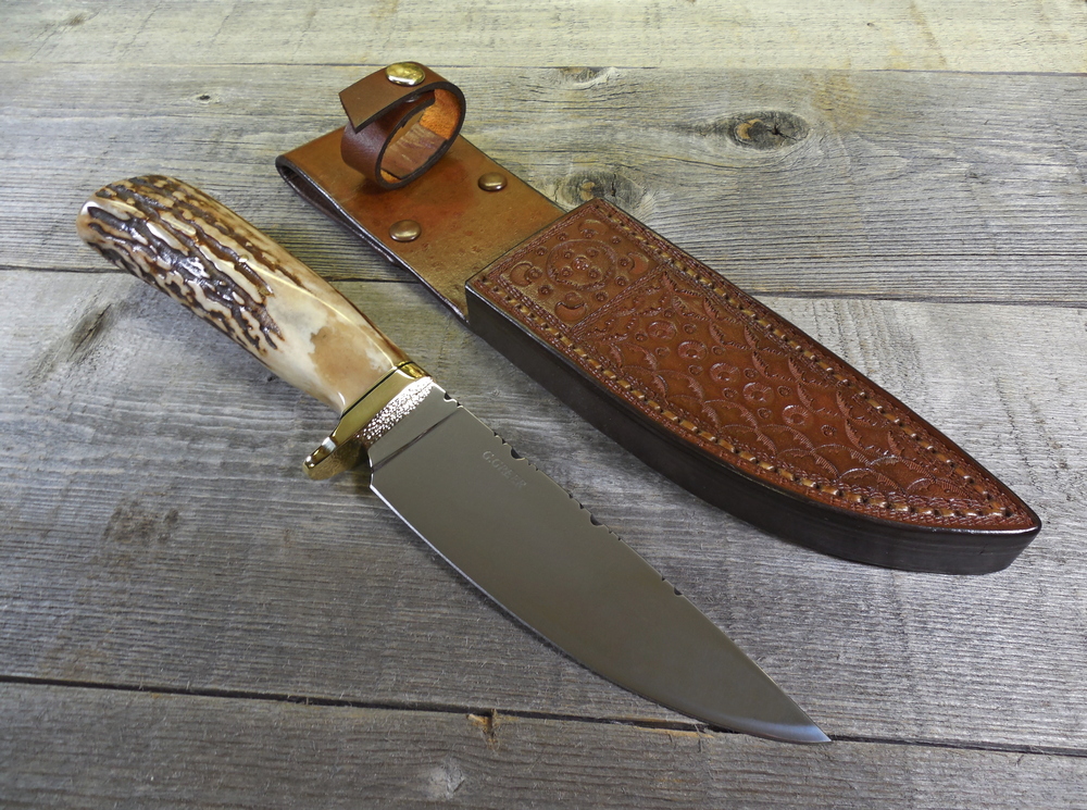 Elk horn hunting knife beside custom fitted leather sheath